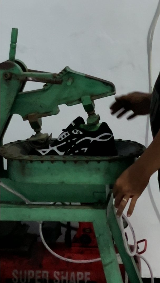 Mesin press sepatu hijau sedang menekan sneakers hitam di workshop Core Manufacturing